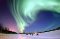 A blue-green-aurora swirling over a snowy landscape